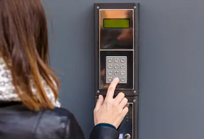 femme dans la rue sonnant à un interphone