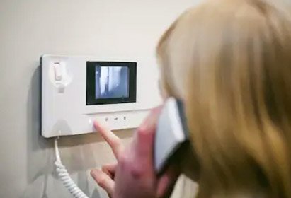 personne ouvrant l'entrée de sa propriété à l'aide d'un interphone vidéo